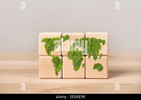 Wooden cubes on a gray background with a green world map. Sustainable development and business based on renewable energy. Earth day concept and green recycling. Ecology concept. World Environment Day Stock Photo