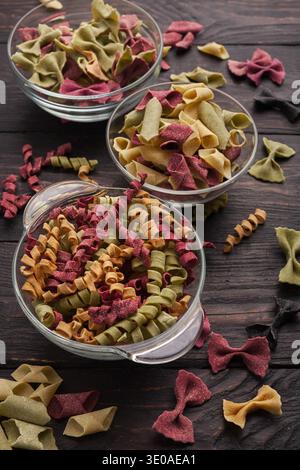 Various colorful pasta in glass bowls on wooden background Stock Photo