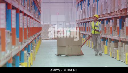 Scanning worker wearing yellow hard hat hi-vis vest with scanner by pallet jack, copy space Stock Photo