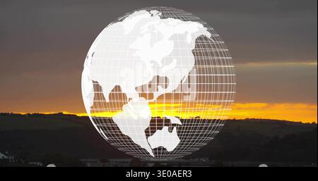 Displaying wireframe globe hovering over sunset hills, showing gold horizon band and silhouettes Stock Photo