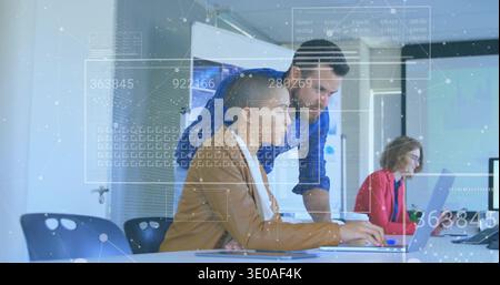 Vertical video: Collaborating team in brown blazer, blue shirt typing on laptop at office with HUD Stock Photo
