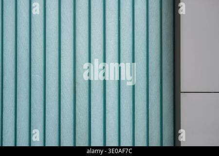 Modern architecture, architectural detail featuring a vertical glass louver system. Textured teal panels create a rhythmic minimalist facade. Stock Photo
