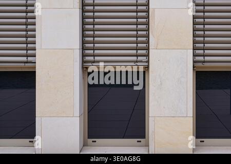 Modern Architecture. Tan stone facade with dark windows and horizontal shutters. Precise geometric symmetry. Modern urban architectural design Stock Photo