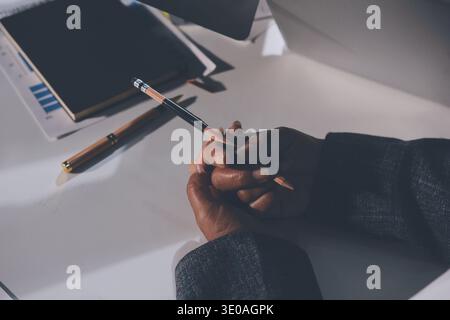 business documents on office table with tablet, smart phone and laptop and two colleagues discussing data Stock Photo