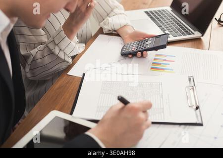 Business colleagues checking documents and using calculator Stock Photo