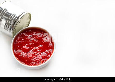 Fresh tomato sauce in a white bowl and a metal can isolated on a white background. Overhead view. Stock Photo
