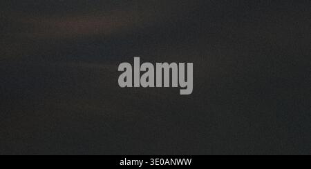 A dark, almost black textured surface featuring a dense, fine grain pattern. Subtle hints of brown or dark gold tones are visible across the surface, Stock Photo