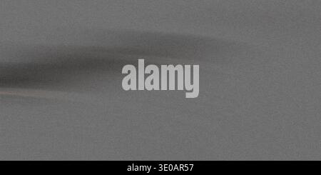 A uniform, grainy, monochromatic gray background texture featuring a horizontal, slightly darker, smudged area running across the center, giving the a Stock Photo