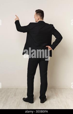 Businessman writing on empty wall back view Stock Photo