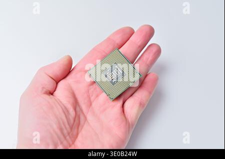 Close-up of a computer processor chip held in a person's hand against a white background Stock Photo