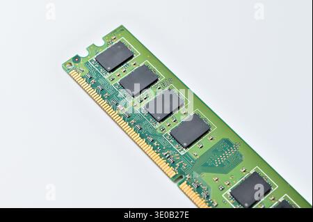 Close-up of a green computer RAM module with black memory chips on a white background Stock Photo