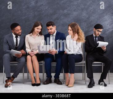 Multicultural young businesspeople using laptops and smartphones Stock Photo
