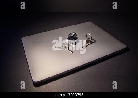 Open padlock and keys on a closed laptop, conceptual image of cybersecurity, access management, device security and potential vulnerability in digital Stock Photo