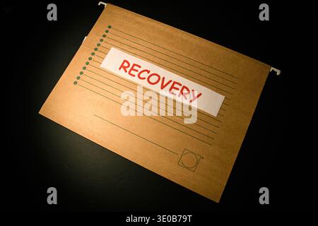 File folder labeled recovery on a dark background, conceptual image of data recovery, incident response, disaster recovery and secure document restora Stock Photo
