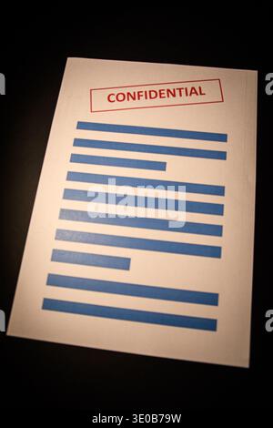 Confidential document with redacted lines on a dark surface, conceptual image of privacy, confidential information, data protection and document secur Stock Photo