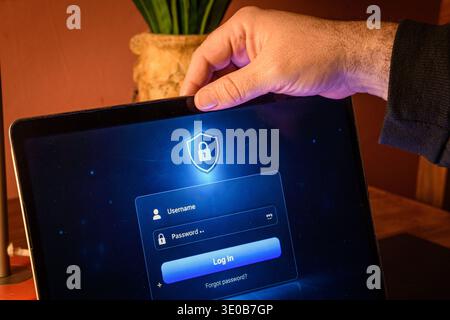 Hand holding a laptop screen with login form and lock icon, conceptual image of secure access, authentication, account protection and cybersecurity. Stock Photo