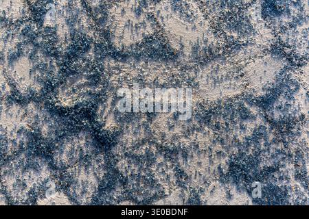 Blue crystal texture on rough surface. Abstract close-up of scattered blue crystals on a pale textured background, creating a sparkling mineral Stock Photo