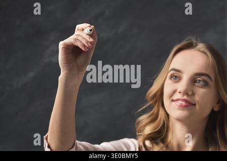 Smiling woman writing something in air with marker Stock Photo