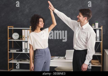 Colleagues giving high five at office Stock Photo