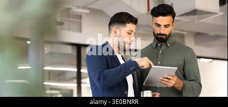 Wide view of two businessmen reviewing project data on tablet Stock Photo