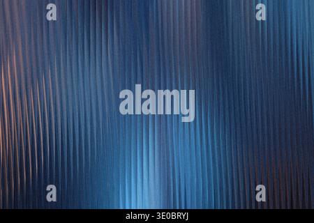 A textured blue background with vertical ribbed patterns and subtle orange light highlights Stock Photo
