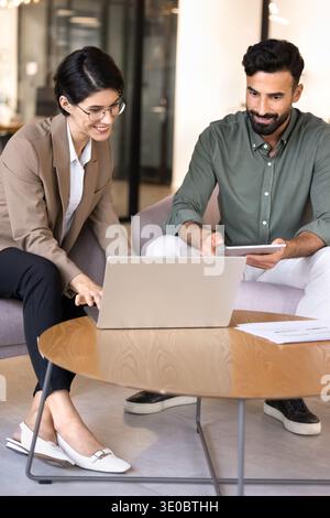 Colleagues collaborating on business project using laptop and tablet Stock Photo