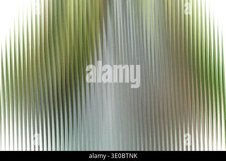 A closeup abstract view of textured glass with vertical ribbed patterns, showing a gradient of light and subtle green hues Stock Photo