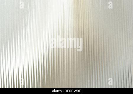A textured background of vertical corrugated metal with a bright light reflecting off the surface, creating a shimmering effect Stock Photo