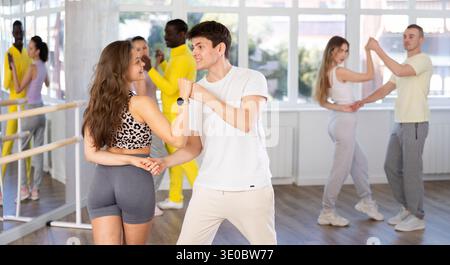 Men and women are standing next to each other and dancing in pair of salsa. Students practice repeating movements of pair dance Stock Photo