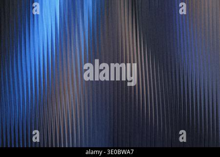 A textured surface with vertical ribbed patterns, illuminated by a gradient of deep blue to dark gray, creating a sense of depth and abstract beauty Stock Photo