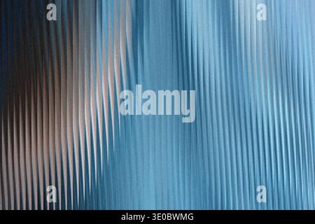 A textured surface with vertical ribbed patterns, transitioning from a dark, muted tone on the left to a bright, shimmering blue on the right, creatin Stock Photo