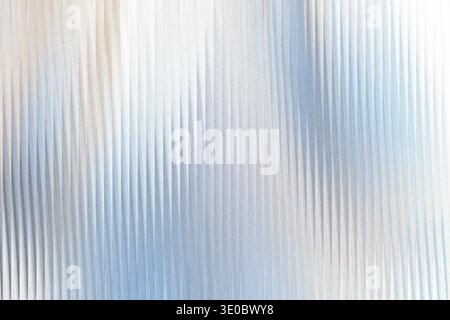 A textured background with vertical ribbed lines, shimmering with soft light and subtle color gradients of blue and beige Stock Photo