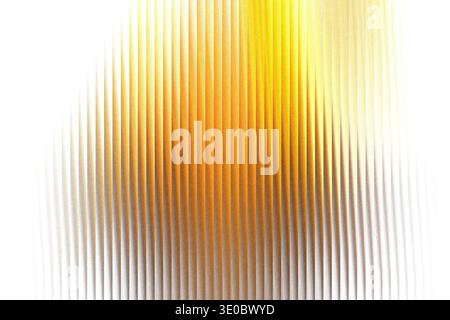 A closeup view of textured glass with vertical ridges, illuminated by a warm golden light that creates a gradient effect Stock Photo