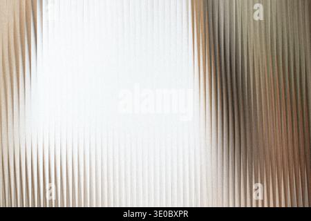 A closeup abstract view of textured glass with vertical ridges, creating a pattern of light and shadow Stock Photo