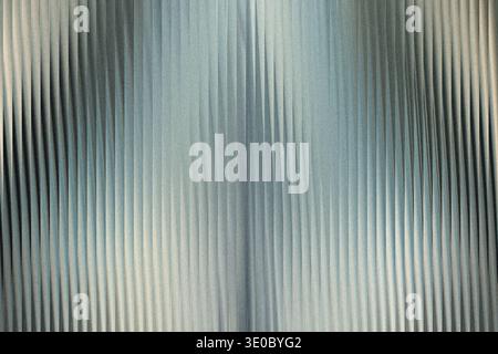 A textured metallic surface with vertical ribbed patterns, featuring a gradient of light and shadow Stock Photo
