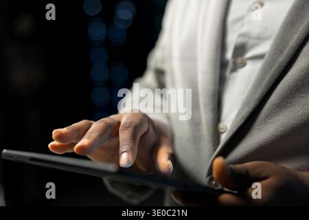 Close up of engineer in server farm checking recovery plan on tablet, evaluating diagnostic reports. Data center IT expert reviewing network configuration, making sure rigs are functioning optimally Stock Photo