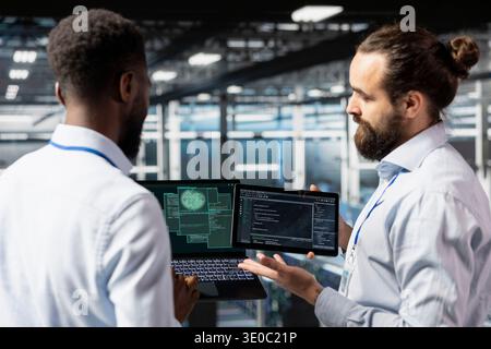 Software developers sharing ideas in data center with AI tools, monitoring neural network systems on industrial platform. Server farm team overseeing deep learning processes, server clusters. Stock Photo