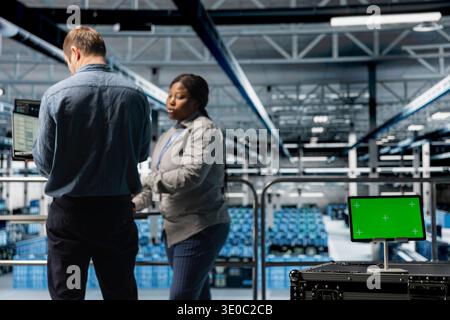Team of data center system administrators using green screen tablet to reduce downtime. Server farm colleagues monitoring hardware performance using software on chroma key device Stock Photo