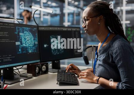 Data center developer using artificial intelligence machine learning tech. African american woman in server farm using AI programming language on computer to update equipment Stock Photo
