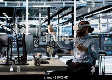 Engineer in data center using VR headset to update storage arrays software, configuring network virtualization. Man in server room using virtual reality to maintain stable performance Stock Photo
