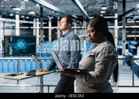 Teamworking data center technicians installing and upgrading hardware components. Server farm coworkers doing job tasks, implementing backup solutions to protect against data loss Stock Photo