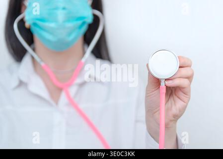 Close up doctor wearing medical mask holding stethoscope toward camera, healthcare checkup and clinical diagnosis concept Stock Photo