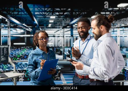 Server farm diverse coworkers doing infrastructure AI machine learning automatization. Data center computer scientists collaborating to maintain servers using artificial intelligence tools. Stock Photo
