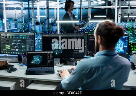 Programmer working in data center with hardware managing AI training datasets. IT worker overseeing machine learning tech in server farm supporting scalable infrastructure for AI apps Stock Photo
