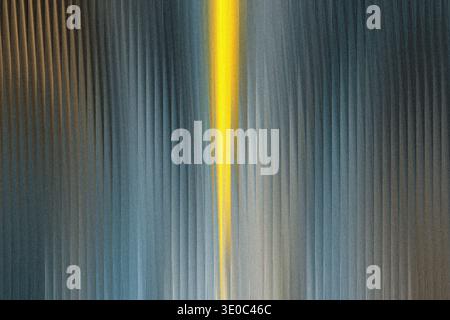 A vibrant yellow beam cuts through a textured, vertical striped background of gray and blue hues, creating a striking abstract visual Stock Photo