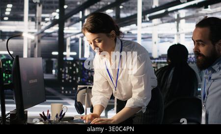 Panicked engineers in data center react to ransomware warning on PC display, scrambling to launch emergency response protocol. IT staff urgently trying to fix hacked infrastructure systems, camera A Stock Photo