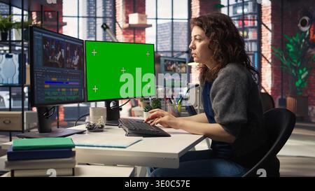 Woman video creator edits a multimedia project next to chroma key at agency office, using professional tech tools and editing software to manage timeline editing and video production. Camera A. Stock Photo