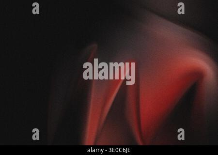 An abstract composition dominated by darkness, where a vibrant red form emerges from the shadows. The entire image has a heavy, grainy texture, creati Stock Photo
