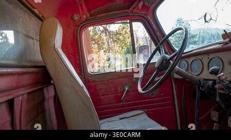 The interior of an antique dump truck that has a cracked windshield and torn seats Stock Photo