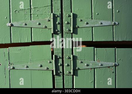Rustic green metal strap hinges used on boat shed gate. Location: Auckland New Zealand Stock Photo